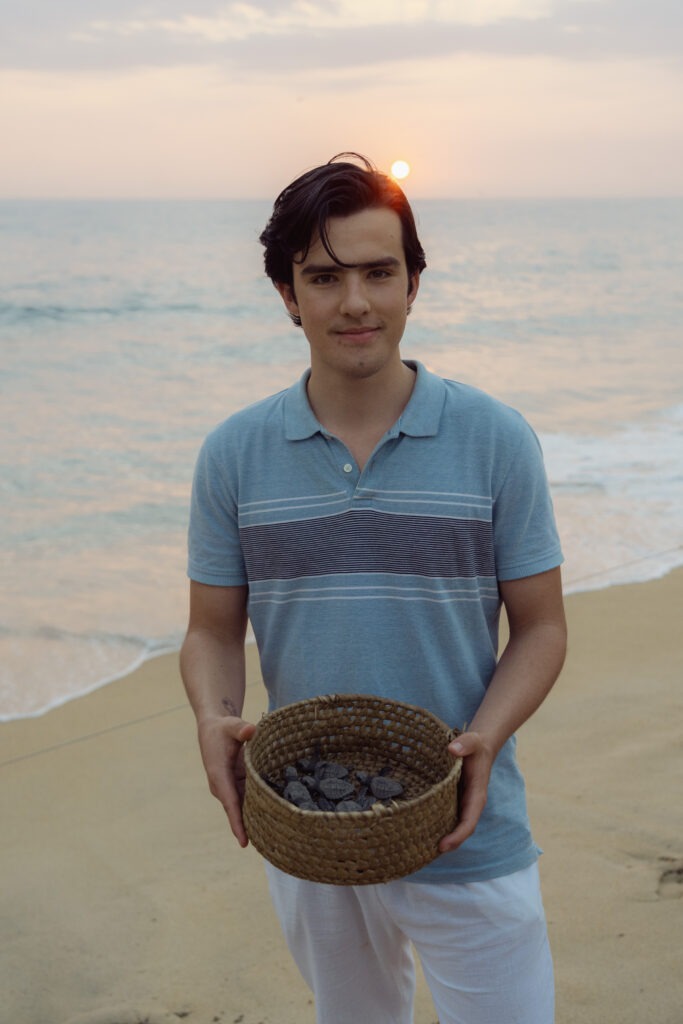 Alex Favero on a beach on the Oaxaca coast, holding a woven basket.